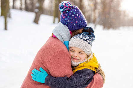 Mother and son hugging outdoors in snowの写真素材
