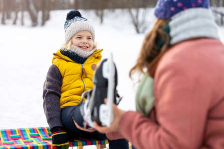 Mother helping son to put on his ice skatesの写真素材