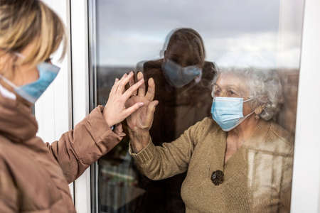 Woman visiting her grandmother in isolation during a coronavirus pandemicの写真素材