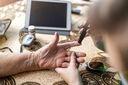 Cropped shot of a nurse doing glucose blood test on senior patient during home visit