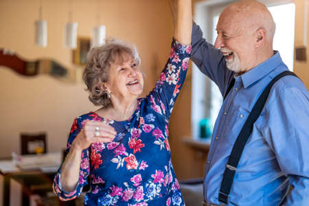 Happy senior couple dancing together at homeの写真素材