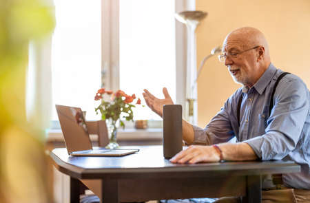 Senior man using Virtual Assistant at homeの写真素材