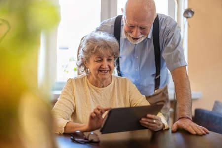 Happy senior couple using digital tablet at home
