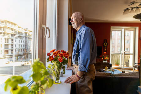 Senior Man Looking Through Window at Homeの写真素材