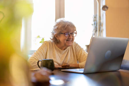 Happy senior woman using laptop at home