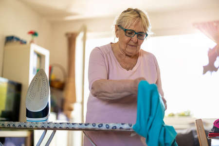 Senior woman at home ironing clothesの写真素材