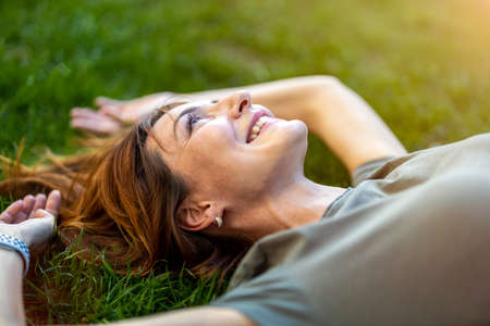 Carefree woman lying on the grass in the sunの写真素材