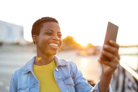 Smiling young woman using smartphone outdoors