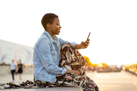 Smiling young woman using smartphone outdoors