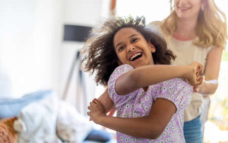 Young girl dancing with her mother at home