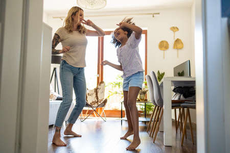 Young girl dancing with her mother at homeの写真素材