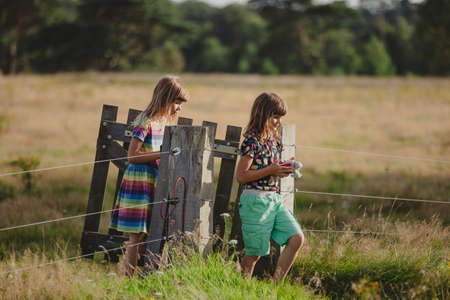 Children walking through a wooden gate in a fieldの写真素材