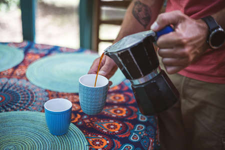 Man pouring coffee from a coffee maker into a cupの写真素材