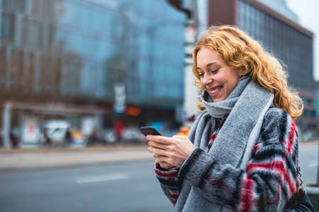 Smiling young woman in the city holding mobile phoneの写真素材