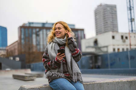 Smiling young woman in the city holding mobile phone