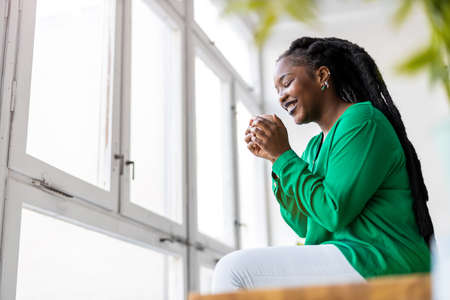Young woman with cup of coffee looking out of window