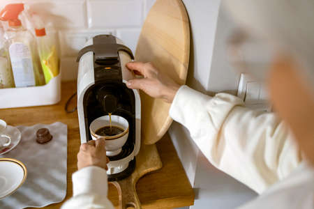 Close up shot of a senior woman preparing coffee at home using an espresso machine