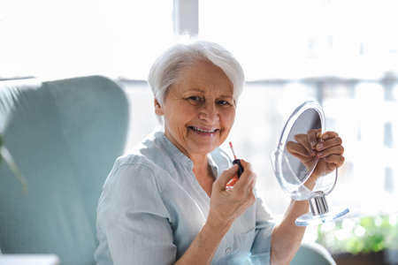 Senior Woman Doing Makeup In Front Of Mirror