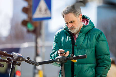 Mature man activating electric scooter from smartphone