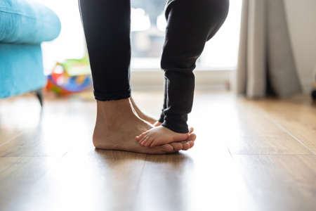 Baby son standing on mothers feetの写真素材