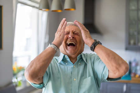 Happy senior man laughing in his home