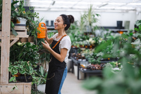Woman working in greenhouse, watering flowersの写真素材