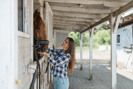 Young woman in a stable with her horseの写真素材