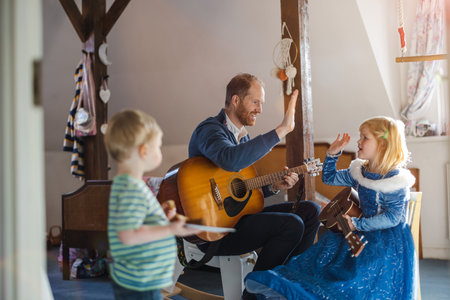 Dad teaching his kids how to play guitarの写真素材