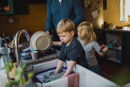 Children helping father washing dishes in the kitchenの写真素材