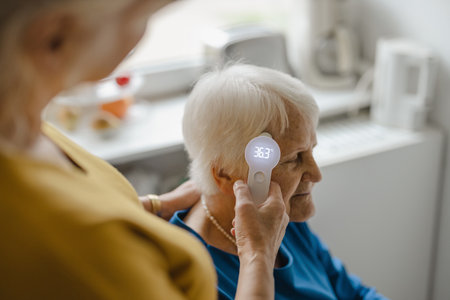 Elderly woman checking temperature on digital thermometer in nursing homeの写真素材
