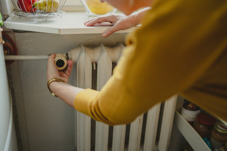 Woman adjusting the temperature of a radiator at homeの写真素材