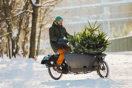 A man carries a Christmas tree on a bicycle in the winter forest.の写真素材