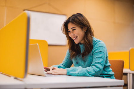 Portrait of smiling businesswoman using laptop at desk in creative officeの写真素材
