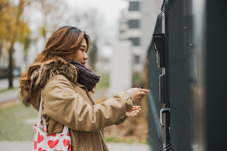 Young woman entering code at gate in urban areaの写真素材