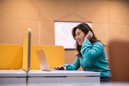 Portrait of a happy young businesswoman using laptop computer at officeの写真素材
