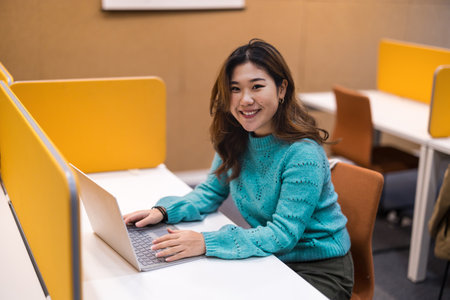 portrait of young asian woman using laptop while sitting in cafeの写真素材
