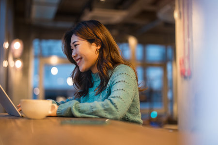 Asian woman using laptop computer at night in the coffee shop. Business and technology concept.の写真素材