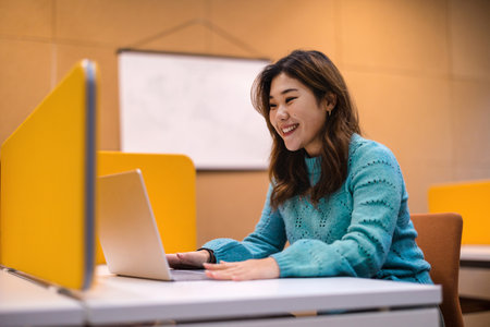 Portrait of smiling young businesswoman using laptop at desk in officeの写真素材