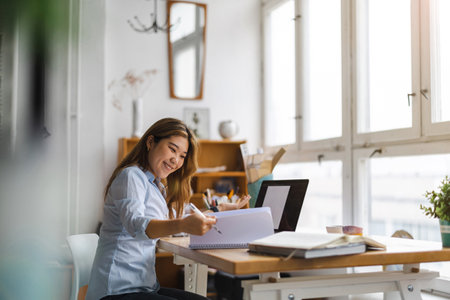 Young businesswoman working at her desk in her office. She is using a laptop and smilingの写真素材