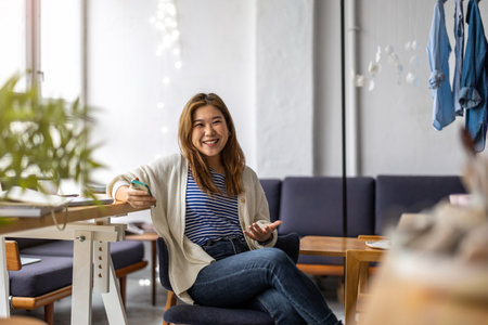 Smiling woman using mobile phone while sittingの写真素材