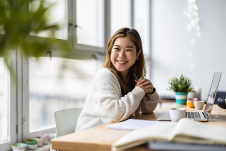Portrait of a smiling young businesswoman sitting at her desk in officeの写真素材