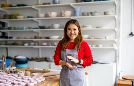Portrait of smiling young female potter standing in pottery workshopの写真素材