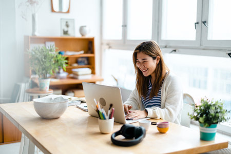 Smiling asian businesswoman working on laptop at desk in officeの写真素材
