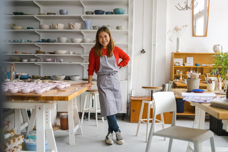 Portrait of a smiling female potter standing in her studio.の写真素材