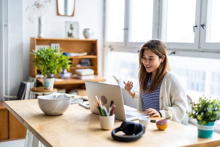 smiling asian businesswoman using laptop at workplace in modern officeの写真素材