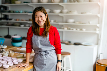 Portrait of happy Asian female potter standing in pottery workshopの写真素材