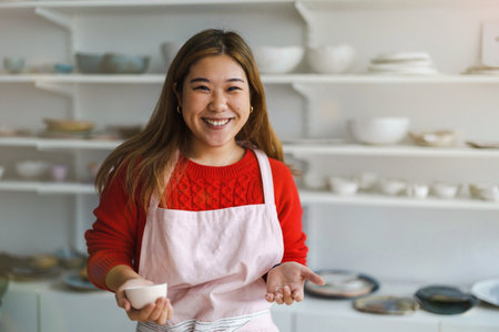 portrait of smiling young asian woman in apronの写真素材