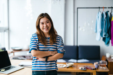 portrait of smiling young fashion designer standing with crossed arms in officeの写真素材