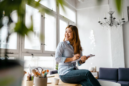 Portrait of a young woman sitting at the table in the officeの写真素材