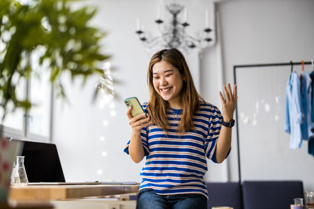 young asian woman using mobile phone in modern office, lifestyle conceptの写真素材